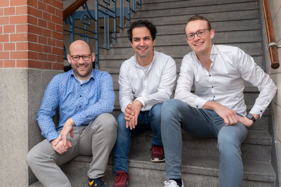 A group photo of Flurin Egger, Endre Davids, and Bram Lenten sitting on stairs.