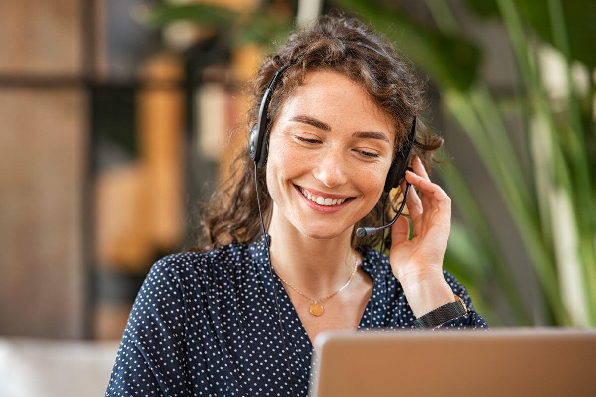 A female callcenter operator wearing a headset smiling at a screen